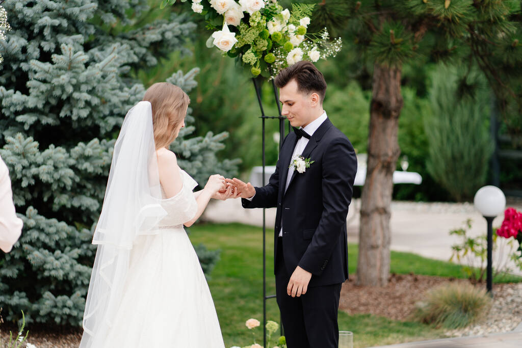 υπαίθρια γαμήλια τελετή σε μια αψίδα ζωντανών λουλουδιών.Νεόνυμφοι αντάλλαξαν δαχτυλίδια - Φωτογραφία, εικόνα