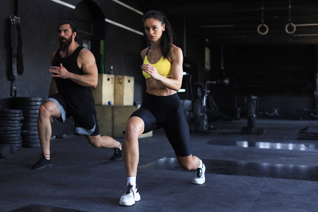 Fitness couple in sportswear doing squat exercises at gym - Photo, Image
