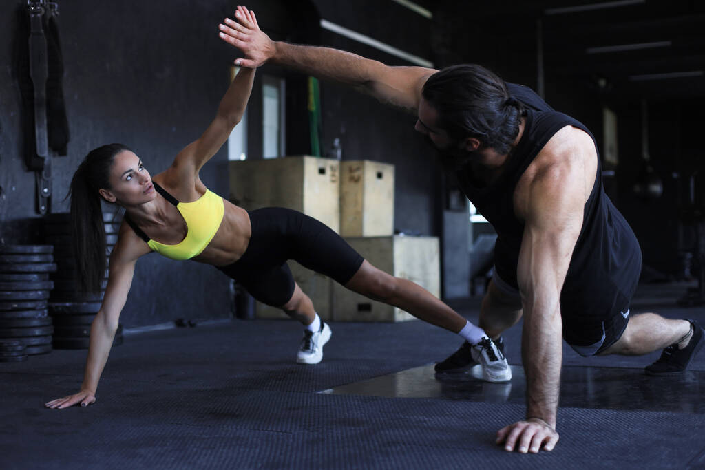 Deportiva pareja haciendo flexiones y dando choca entre sí en el gimnasio - Foto, Imagen