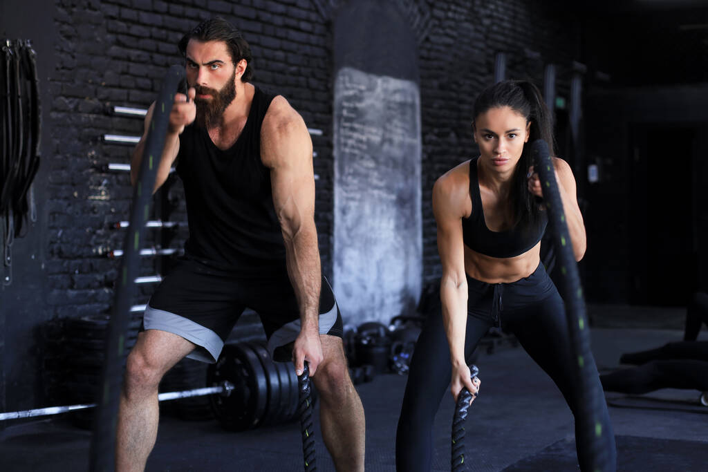 Jeune couple athlétique avec corde de combat faire de l'exercice dans la salle de fitness d'entraînement fonctionnel - Photo, image