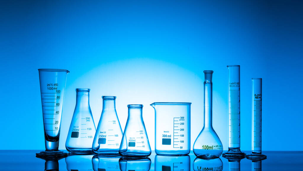 Eine Vielzahl von Glasflaschen und Laborgeräten auf blauem Grund - Foto, Bild