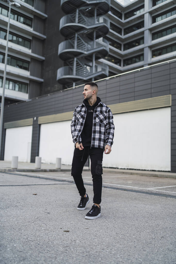 A vertical shot of a young trendy male posing in a streetwear outfit - Photo, Image