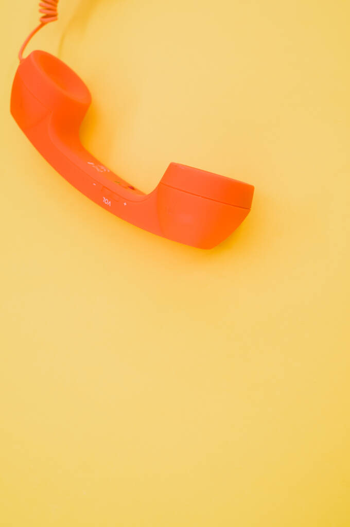 Pionowe ujęcie klasycznego pomarańczowego słuchawki na pastelowym żółtym tle dla przestrzeni kopii - Zdjęcie, obraz