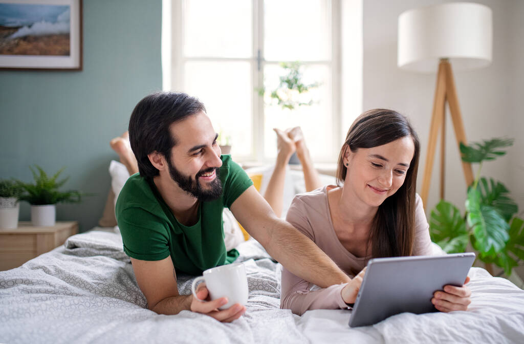 Молода пара закохана, використовуючи планшет на ліжку вдома
. - Фото, зображення