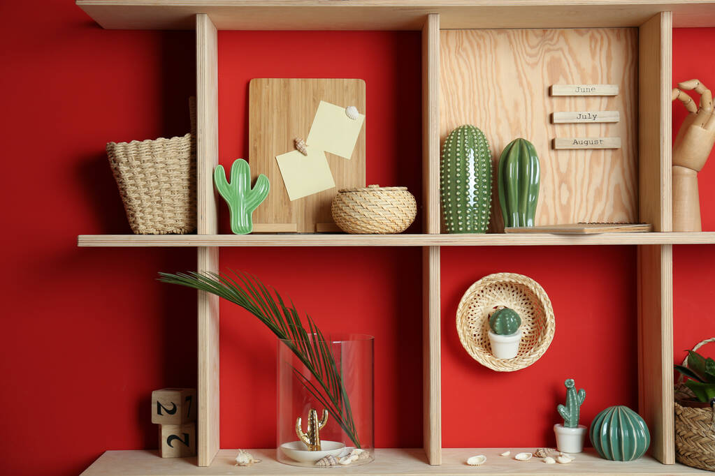 Stylové dřevěné police s dekorativními prvky na červené stěně - Fotografie, Obrázek
