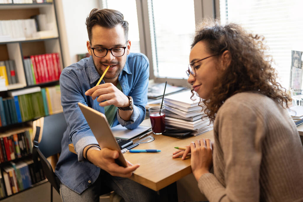 Счастливые коллеги смотрят на ноутбук во время работы в креативном офисе - Фото, изображение