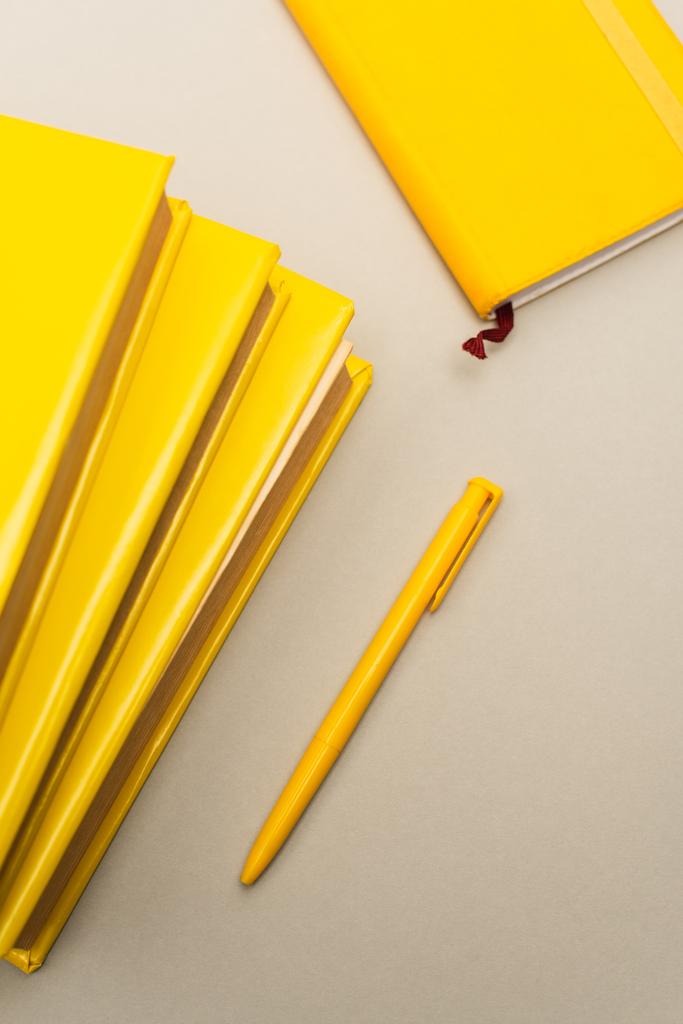 ylhäältä näkymä keltaisia muistikirjoja ja kynä eristetty harmaa - Valokuva, kuva