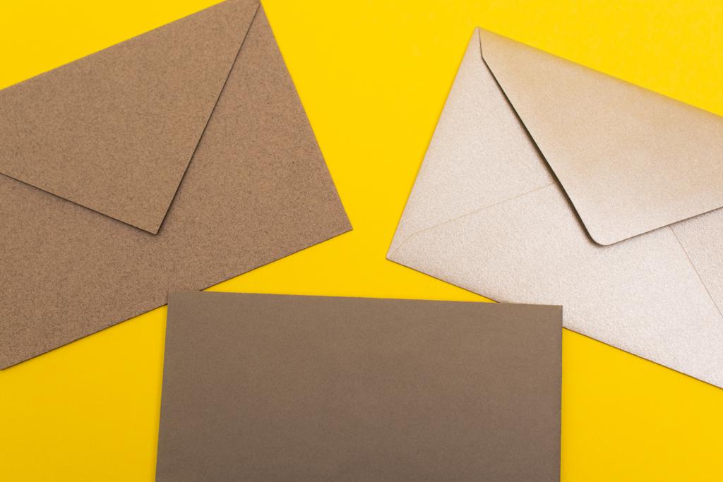 верхний вид бумажных конвертов, изолированных на желтом - Фото, изображение