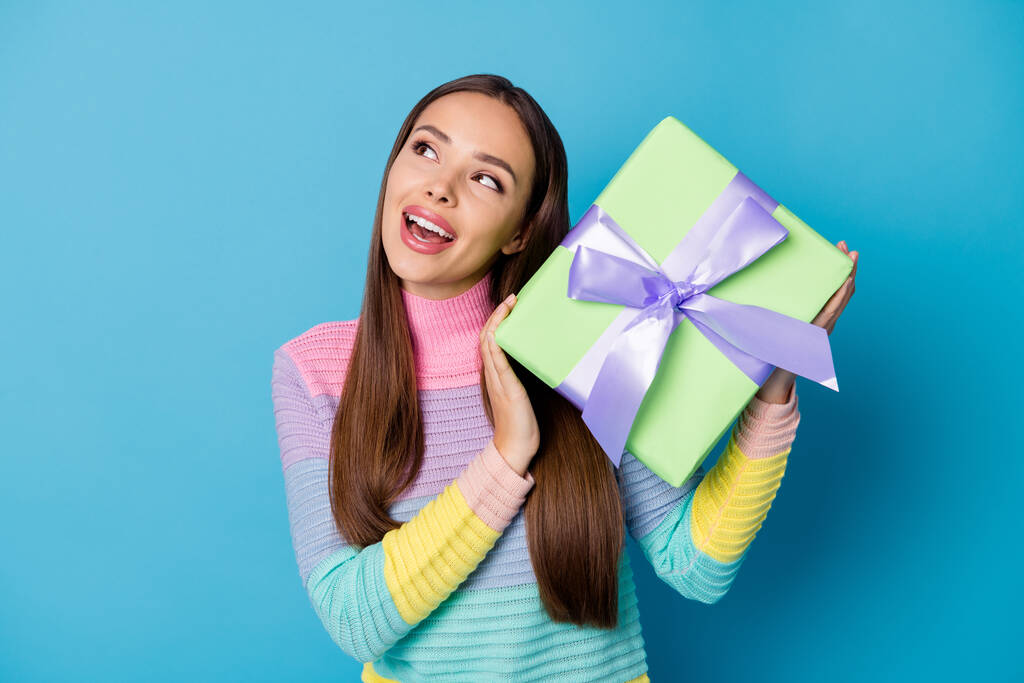 Foto van nieuwsgierig meisje krijgen geschenk doos 14-februari 8-maart voorstellen slijtage trui geïsoleerd over blauwe kleur achtergrond - Foto, afbeelding
