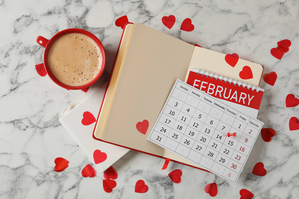 Calendar with marked Valentine's Day, notebooks and cup of coffee on white marble table, flat lay - Photo, Image