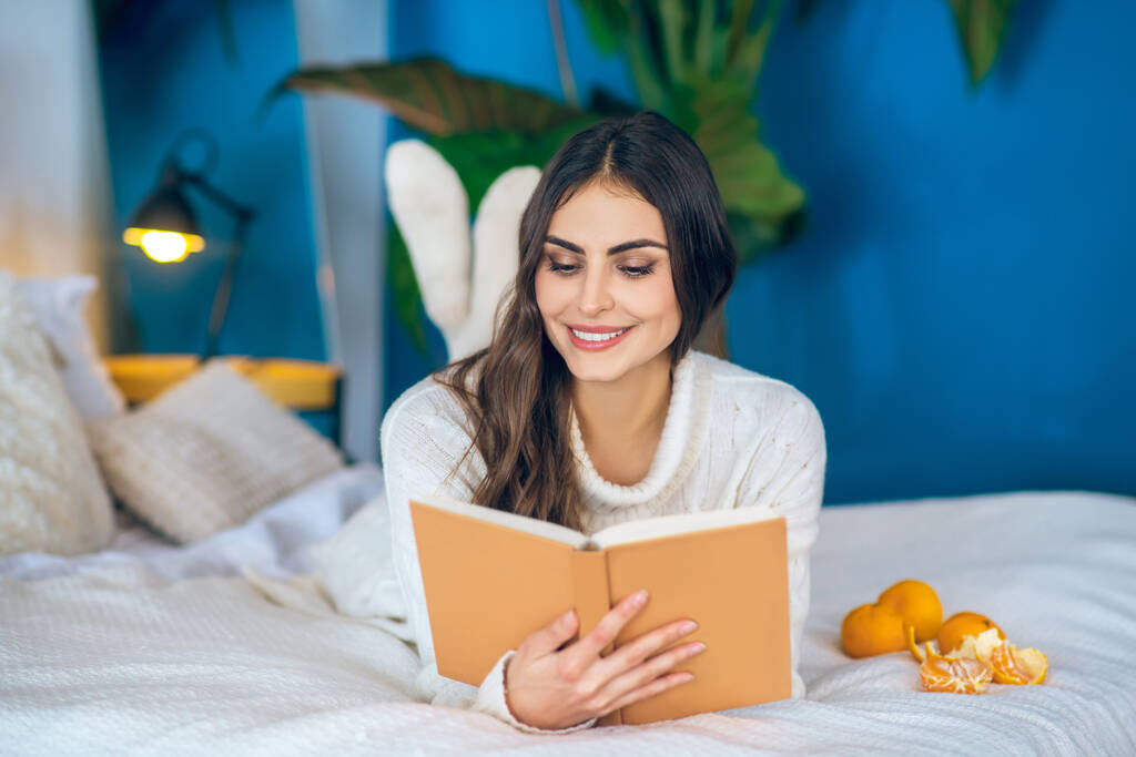 Jonge mooie vrouw die een boek leest en lacht - Foto, afbeelding
