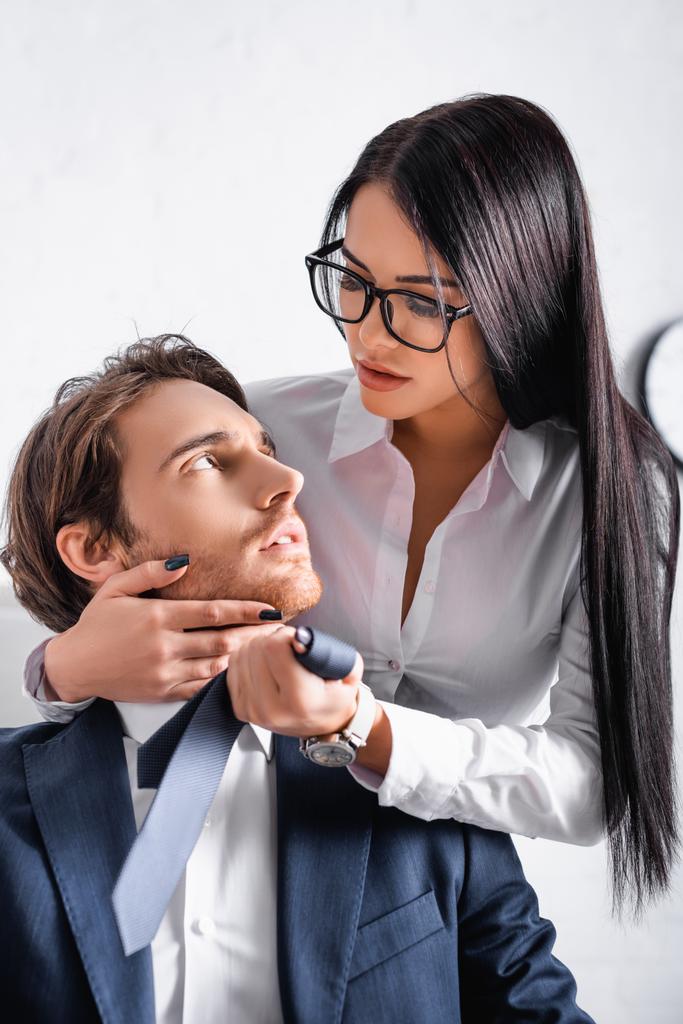 zmysłowa brunetka bizneswoman dotykając twarz kolega podczas uwodzenia go w biurze - Zdjęcie, obraz