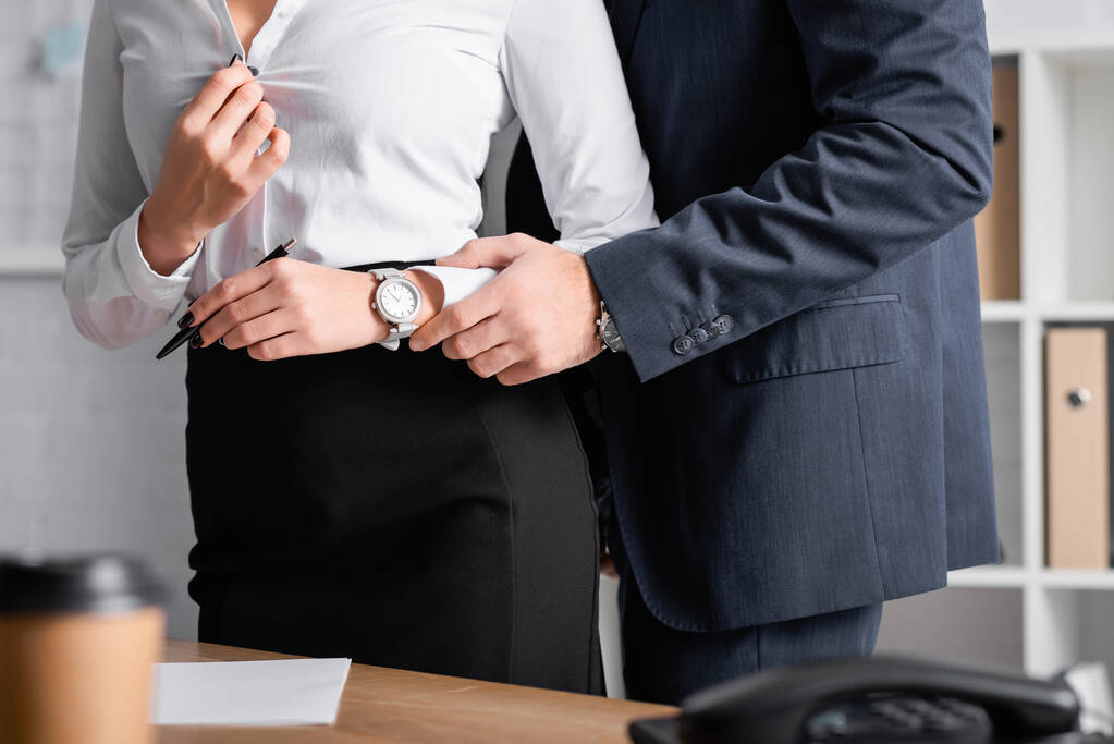 μερική άποψη του επιχειρηματία αγγίζοντας το χέρι του αισθησιακού γραμματέα ξεκούμπωμα μπλούζα, θολή πρώτο πλάνο - Φωτογραφία, εικόνα