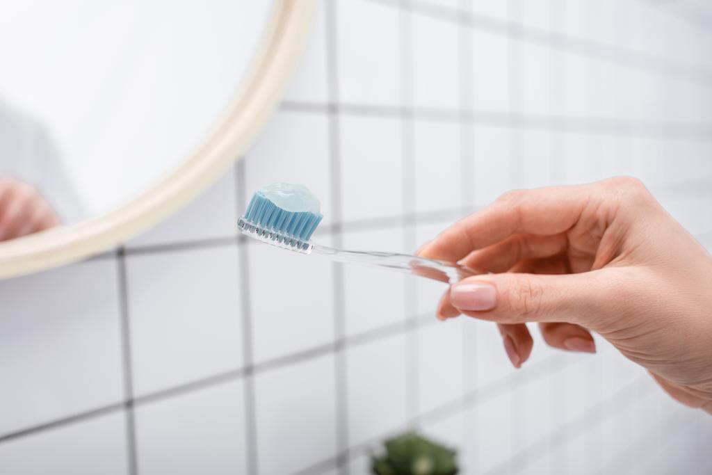 καλλιεργημένη άποψη της γυναίκας που κρατά οδοντόβουρτσα με οδοντόκρεμα στο χέρι - Φωτογραφία, εικόνα