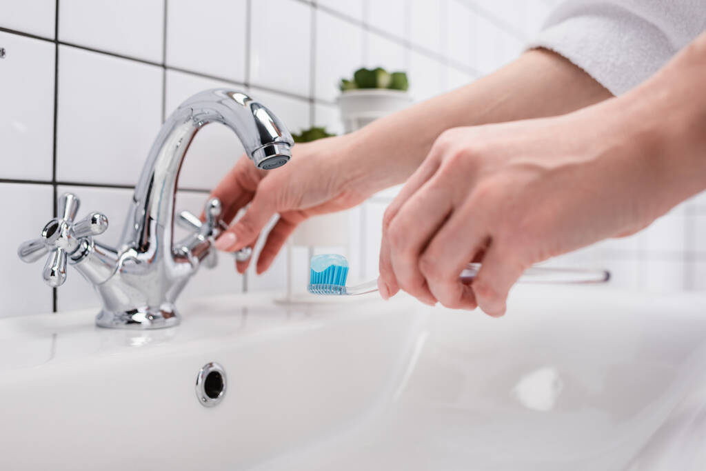 vue recadrée de la femme tenant une brosse à dents dans la salle de bain - Photo, image