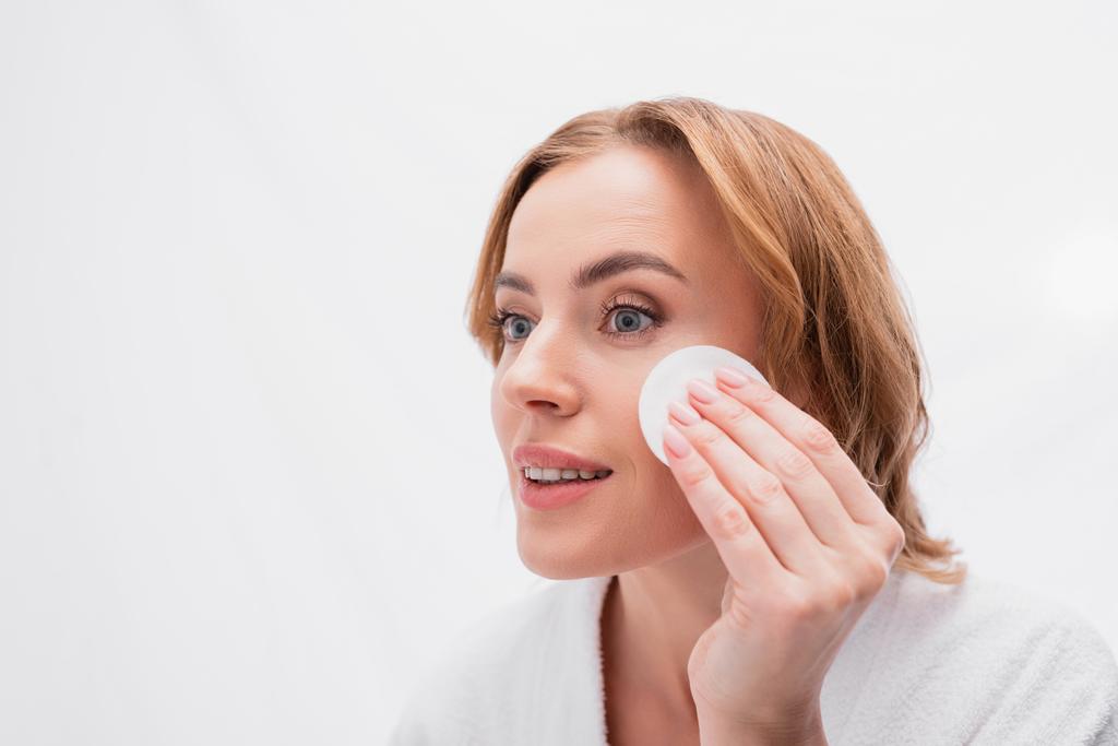 positive woman applying toner with cotton pad on face  - Photo, Image