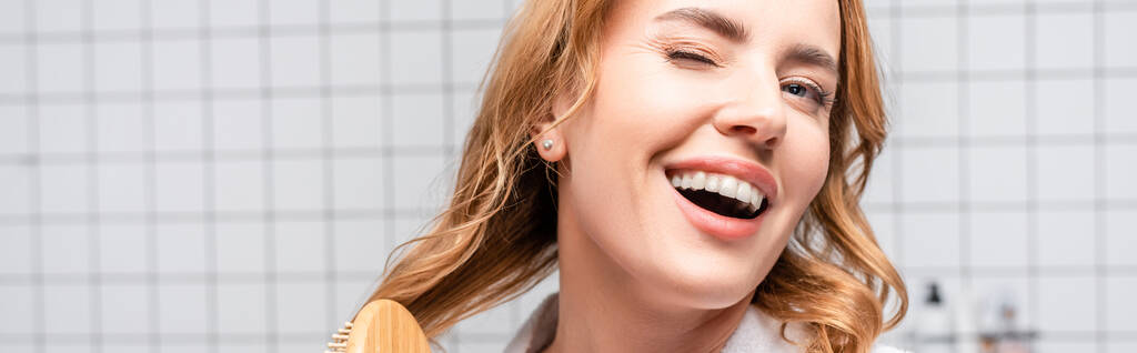 szczęśliwa kobieta uśmiechnięta i szczotkująca włosy w łazience, sztandar - Zdjęcie, obraz