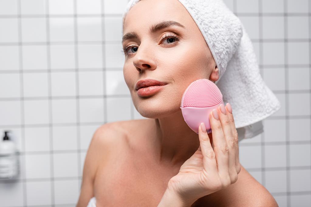 Frau in Handtuch auf dem Kopf mit Reinigungssilikonbürste im Badezimmer - Foto, Bild