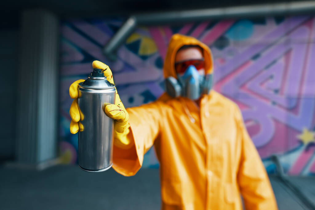 Graffiti artista apuntando pintura en aerosol puede a la cámara - Foto, Imagen