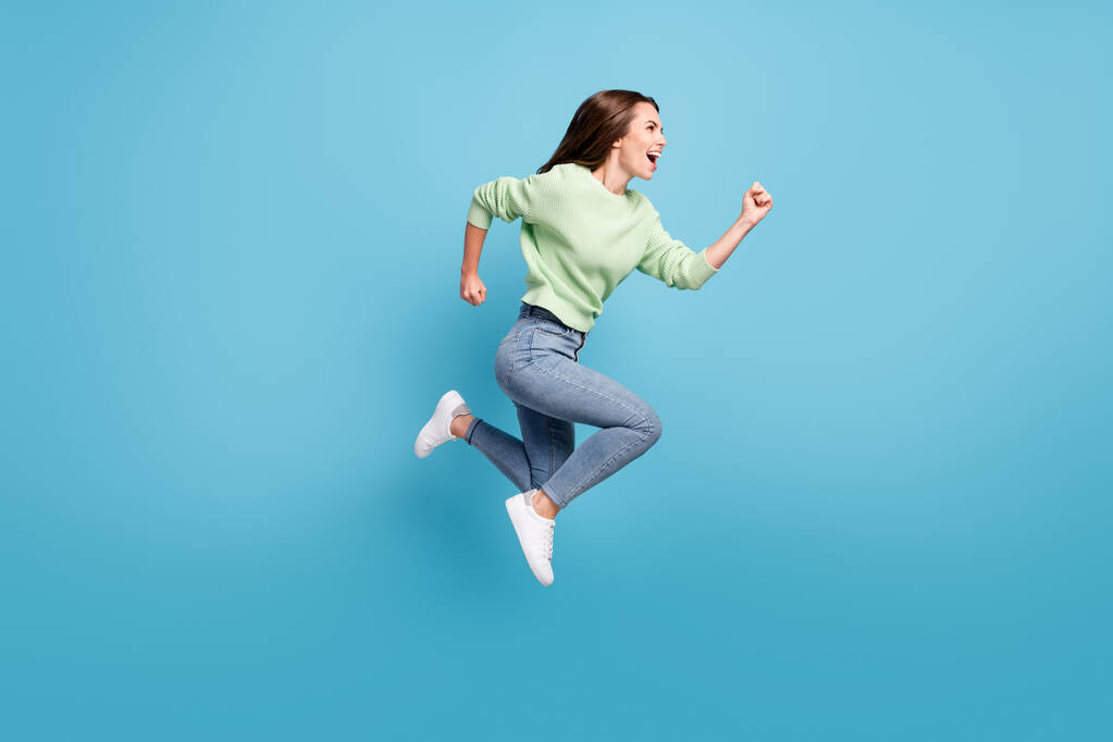 Pełna długość ciała rozmiar boczny profil zdjęcie aktywnej pozytywnej dziewczyny biegnącej do przodu spiesząc się skoków wysoki uśmiechnięty odizolowany na żywy niebieski kolor tła - Zdjęcie, obraz