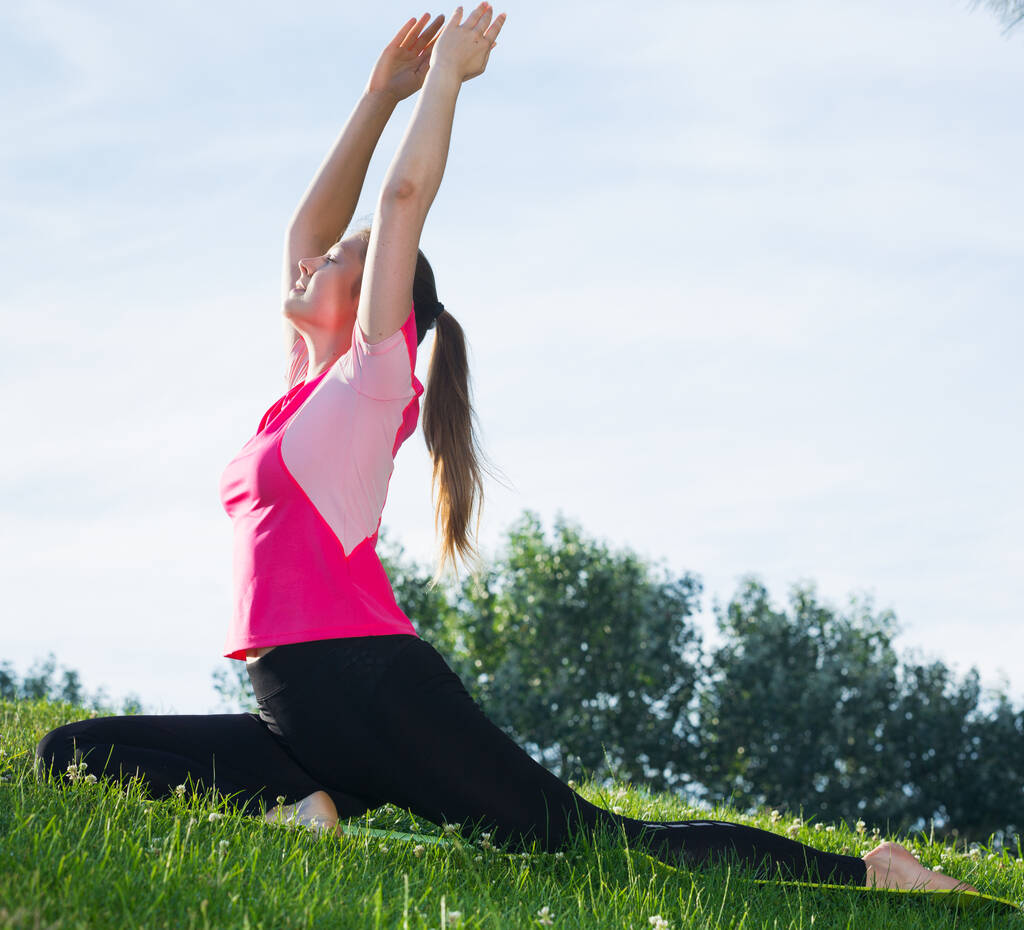 Vrouw 20-30 jaar oud oefent stretching in roze T-shirt - Foto, afbeelding
