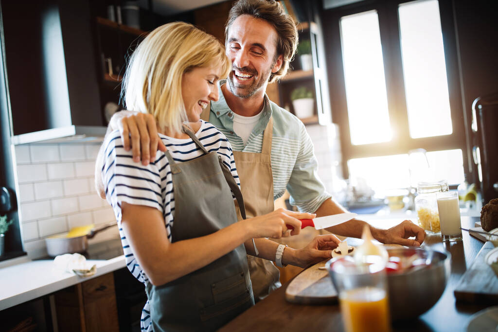 Πορτρέτο του ευτυχισμένου ζευγαριού μαγείρεμα μαζί στην κουζίνα στο σπίτι - Φωτογραφία, εικόνα