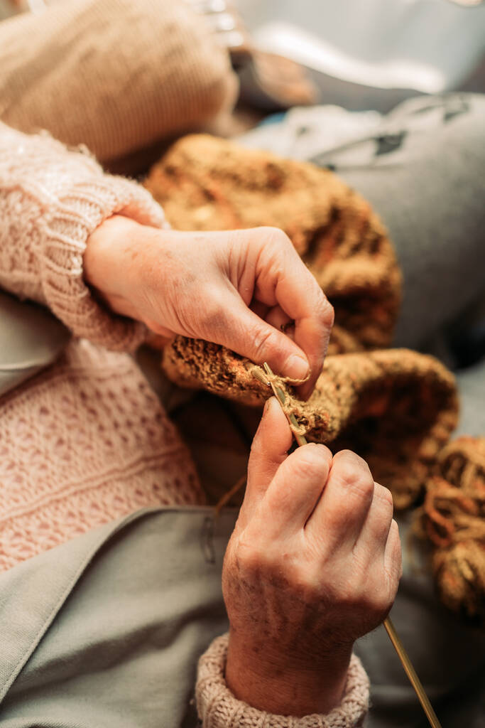 Close-up van de handen van oudere vrouwen breien. Wintertijd. Bovenaanzicht - Foto, afbeelding