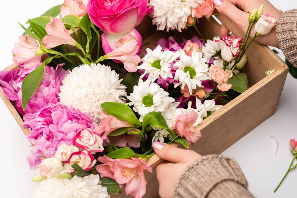 vue recadrée de femme tenant boîte avec variété de fleurs sur blanc - Photo, image