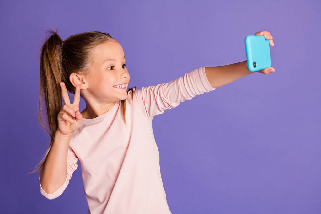 Foto de las colas de pelo castaño niña usar suéter teléfono de retención hacer selfie v-signo aislado sobre fondo de color púrpura - Foto, Imagen