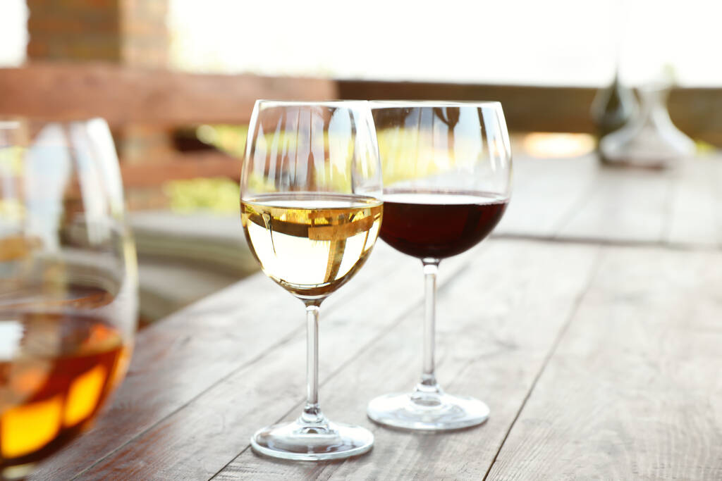 Gläser mit verschiedenen Weinen auf Holztisch im Außencafé - Foto, Bild