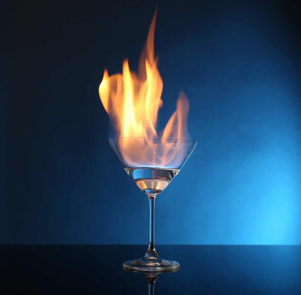 Glas mit brennendem Alkohol auf blauem Hintergrund - Foto, Bild