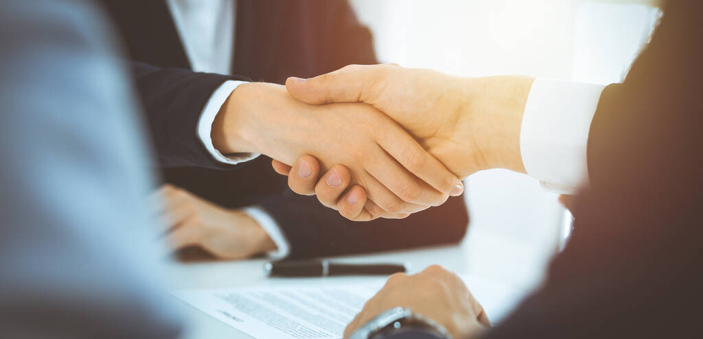 Empresários apertando as mãos terminando reunião ou negociação no escritório ensolarado. Handshake de negócios e conceitos de parceria - Foto, Imagem