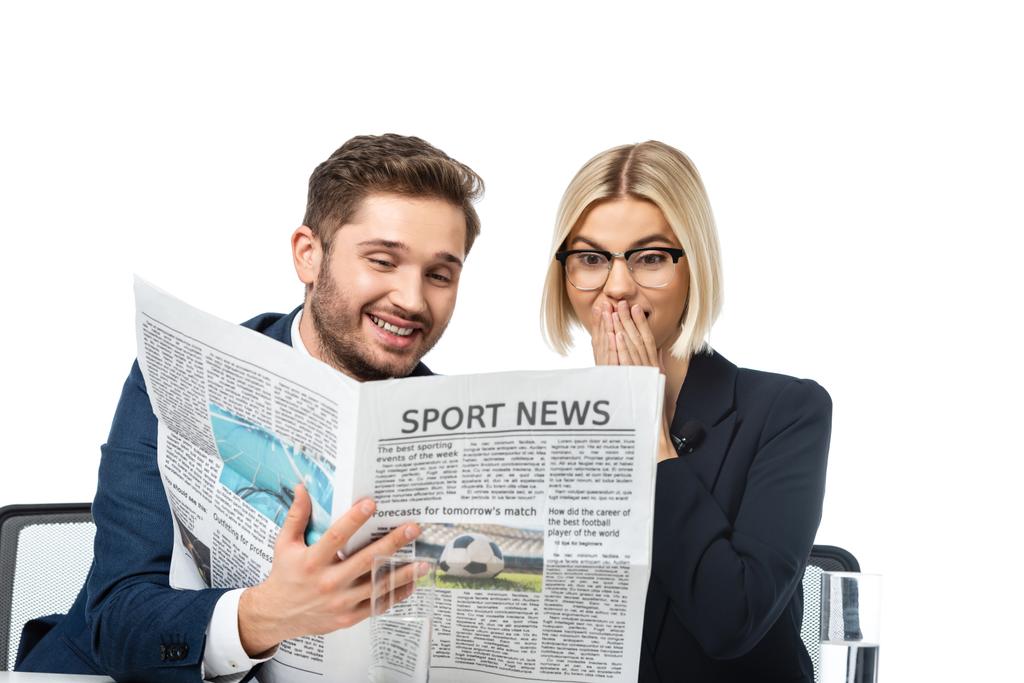 âncora de notícias sorridente mostrando jornal para colega surpreso isolado no branco - Foto, Imagem