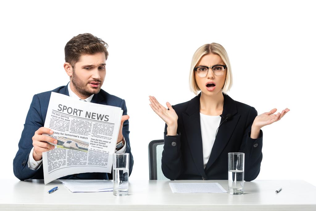 amazed news anchor gesturing near colleague reading sport news isolated on white - Photo, Image