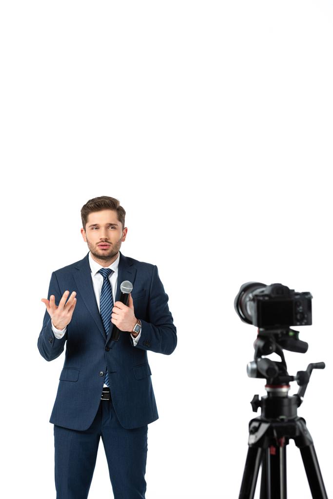 comentarista de noticias con gestos de micrófono mientras habla cerca de la cámara digital en primer plano borroso aislado en blanco - Foto, Imagen