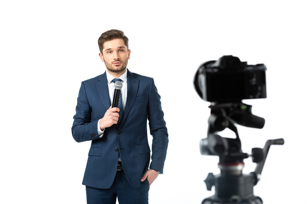 fiatal műsorszolgáltató gazdaság mikrofon közelében digitális fényképezőgép elmosódott előtérben elszigetelt fehér - Fotó, kép