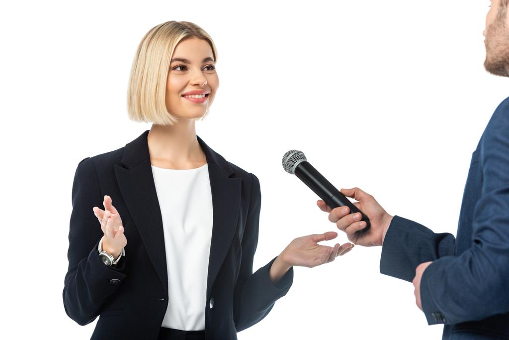 sorridente loira empresária falando perto entrevistador com microfone isolado no branco - Foto, Imagem