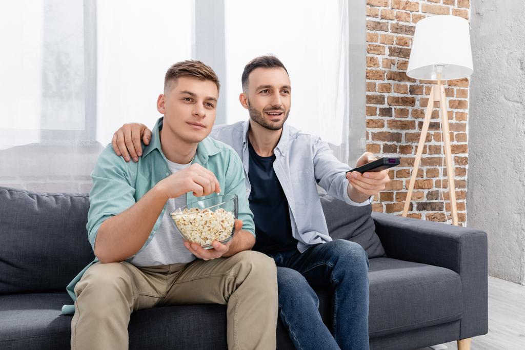 cheerful same sex couple watching film with popcorn  - Photo, Image