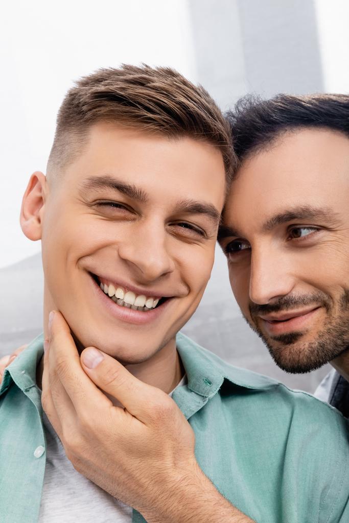 close up of homosexual man touching face of smiling husband at home - Photo, Image
