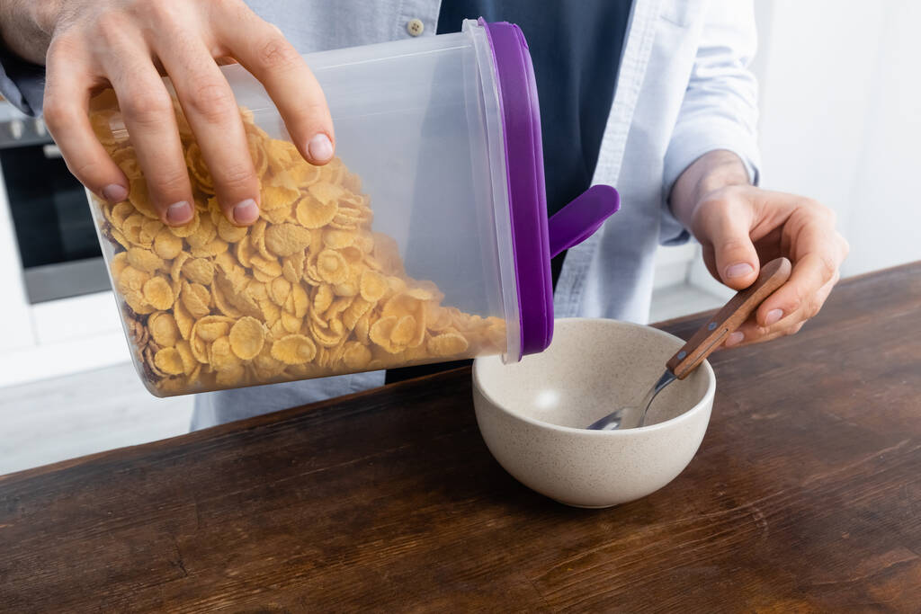 cropped view of man pouring corn flakes in bowl - Photo, Image