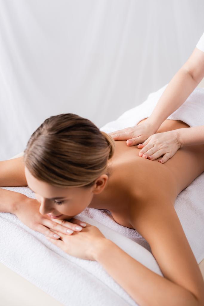 massaggiatore massaggiando schiena del cliente sdraiato sul lettino da massaggio  - Foto, immagini