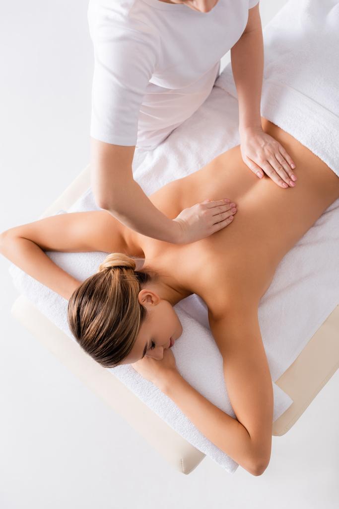 alto ángulo vista de masajista masaje espalda de mujer joven en mesa de masaje  - Foto, imagen