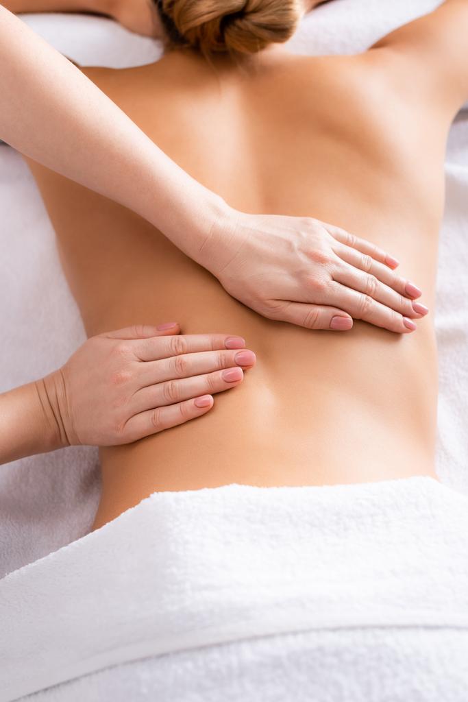 gedeeltelijk uitzicht van masseur masseren client op massage tafel  - Foto, afbeelding
