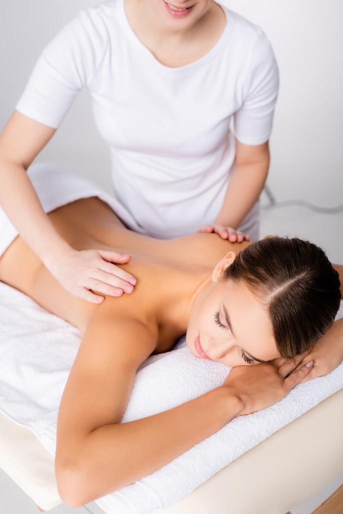 massagista sorridente massageando de volta do cliente na mesa de massagem  - Foto, Imagem
