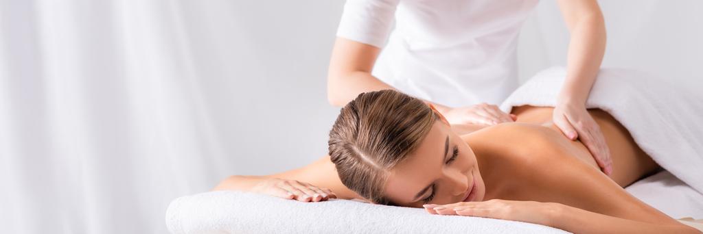 masseur massage blij jonge vrouw op massage tafel in spa salon, banner - Foto, afbeelding