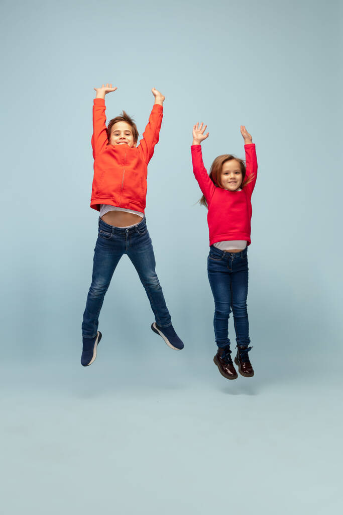 Happy children isolated on blue studio background. Look happy, cheerful, sincere. Copyspace. Childhood, education, emotions concept - Photo, Image
