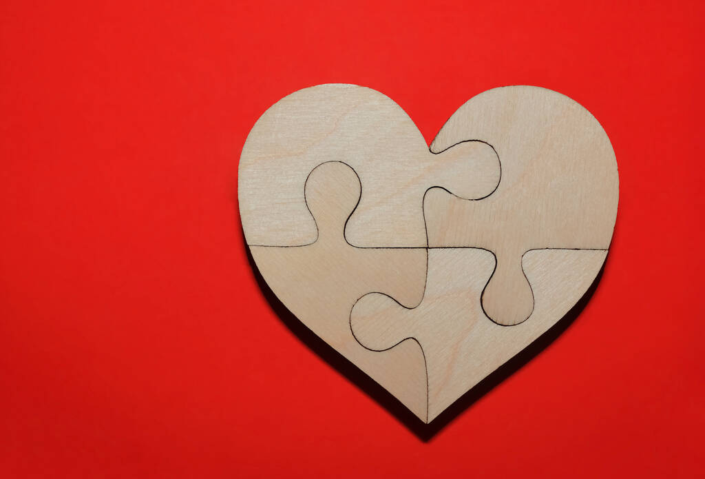 kompletní dřevěné srdce ve tvaru skládačky na červeném papíře pozadí. čtyři kusy.  - Fotografie, Obrázek