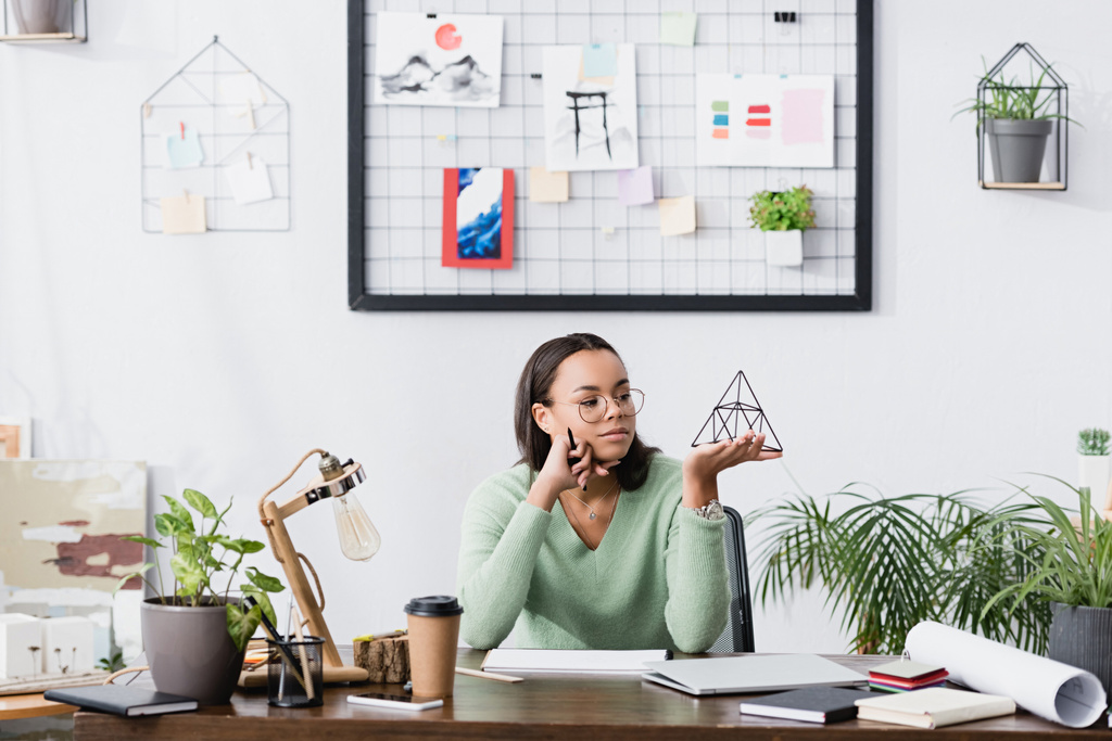 zasněný africký americký designer interiérů drží model pyramidy doma studio - Fotografie, Obrázek