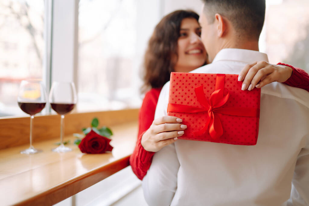 Junges Paar mit Geschenkbox umarmt und feiert Valentinstag. Beziehung, Urlaub, Überraschung und Liebeskonzept. - Foto, Bild