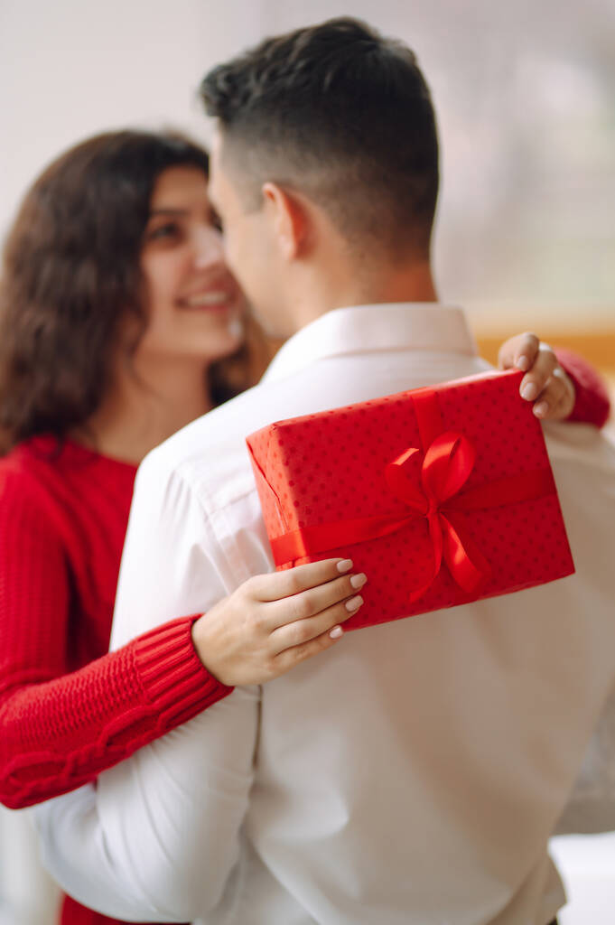 ギフトボックスの抱擁とバレンタインデーを祝う若いカップル。関係、休日、驚きと愛の概念. - 写真・画像